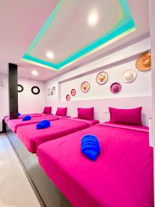 a room with four beds with pink sheets at Sea Smile Green View Pool Villa KRABI Klong Muang in Klong Muang Beach
