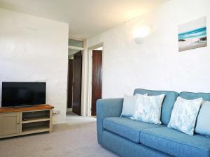 sala de estar con sofá azul y TV en Maple Barn en Porthtowan