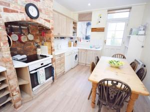 a kitchen with a wooden table and a brick wall at Pepper Pot Cottage in Compton