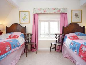 two beds in a room with pink curtains and a window at Pepper Pot Cottage in Compton