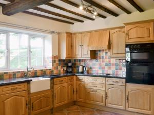 a kitchen with wooden cabinets and black counter tops at Cefnaire in Newtown