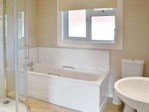Baño blanco con bañera y lavamanos en Roscarrock, en Bradworthy