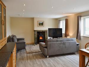 uma sala de estar com sofás, uma televisão e uma lareira em Booth Farm Cottage em Buxton