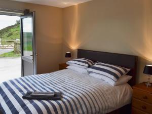 a bedroom with a bed with blue and white stripes at Booth Farm Cottage in Buxton