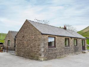 a brick building with windows and a hill in the background at Booth Farm Cottage in Buxton