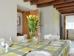 einen Tisch mit Tellern und Gläsern und eine Vase Blumen in der Unterkunft The Mill Farmhouse in Llandybie