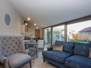 a living room with a blue couch and a kitchen at Woodcrest Barn Cottage - Ukc1065 in Shelfanger