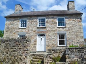 uma antiga casa de pedra com uma porta branca em The Mill Farmhouse em Llandybie
