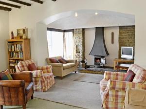 a living room with a couch and chairs and a fireplace at Low Mill Cottage in Grassington