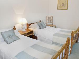 a bedroom with two beds and a table with a lamp at Low Mill Cottage in Grassington