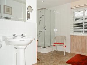 a bathroom with a sink and a shower and a chair at Alices Cottage in Lanehead
