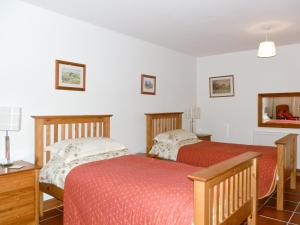 two beds in a room with white walls at Alices Cottage in Lanehead