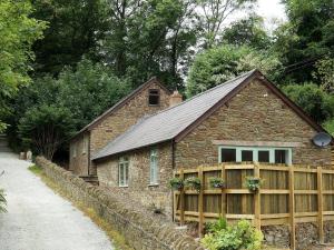 ein Steinhaus mit einem Holzzaun und einem Gebäude in der Unterkunft Burrills View in Horderley