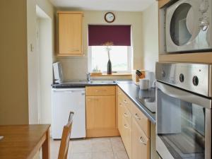 a kitchen with a sink and a microwave at Y Bwthyn in Llangristiolus