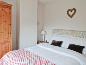 Un dormitorio con una cama blanca con un corazón en la pared en Y Bwthyn, en Llangristiolus