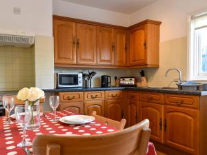 uma cozinha com uma mesa com uma toalha de mesa de bolinhas vermelhas e brancas em Shingle Cottage em Whitstable