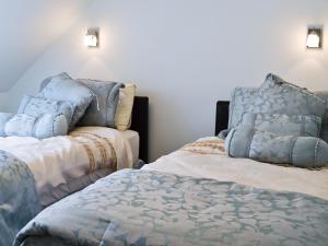 Ampney CrucisにあるDove Cottageのベッド2台が隣同士に設置された部屋です。