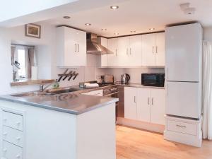 a kitchen with white cabinets and a white refrigerator at Madeleines Barn in Wells next the Sea