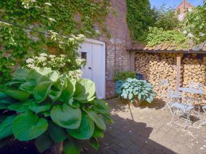 a garden with a white door and some plants at Madeleines Barn in Wells next the Sea