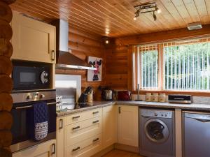 uma cozinha com máquina de lavar e secar roupa numa cabina em Fingask Log Cabin - S4394 em Glenfarg