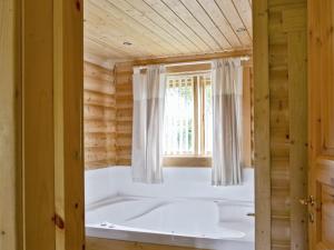 uma grande banheira num quarto com uma janela em Fingask Log Cabin - S4394 em Glenfarg