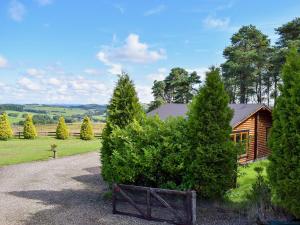 ein von Bäumen und einem Zaun umgebenes Haus in der Unterkunft Fingask Log Cabin - S4394 in Glenfarg