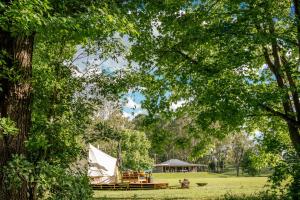 a tent and picnic tables in a park with trees at Unwind Escapes Cabins & Glamping in Dooralong