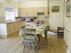 a kitchen with a table with chairs and a kitchen with at Stable Cottage 1 in Rudston