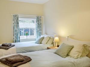 two beds in a bedroom with a window at Stable Cottage 1 in Rudston