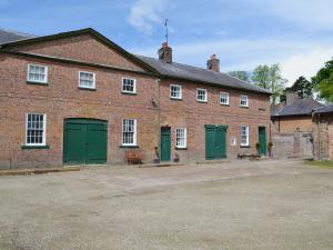 a large brick building with green doors and windows at Stable Cottage 1 in Rudston