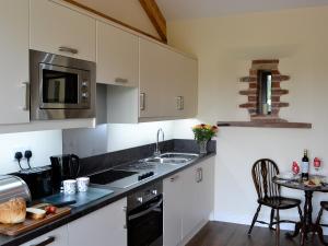 a kitchen with white cabinets and a sink and a table at Brunos Bothy in Wigton