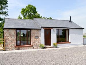 a small stone cottage with a brown door and windows at Brunos Bothy in Wigton