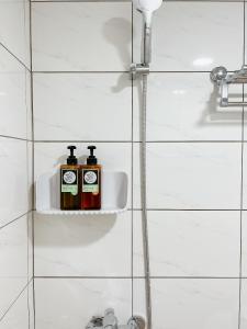 Baño con 2 botellas de jabón en una estantería en Soda White Tainan Homestay en Tainan
