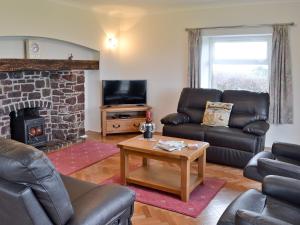 een woonkamer met lederen meubels en een open haard bij Bwthyn Pereos in Llanrhwydrys