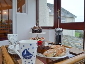 een tafel met borden met gebak en kopjes koffie bij Bwthyn Pereos in Llanrhwydrys