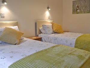 een slaapkamer met 2 bedden met gele en groene lakens bij Bwthyn Pereos in Llanrhwydrys