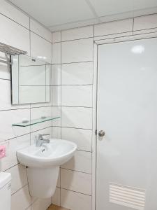 a white bathroom with a sink and a mirror at Soda White Tainan Homestay in Tainan
