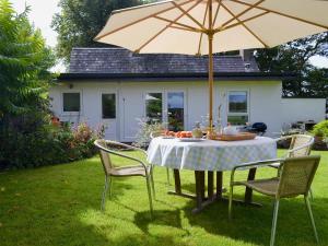 a table and chairs with an umbrella in a yard at Tre Anna Lodge in Dwyran