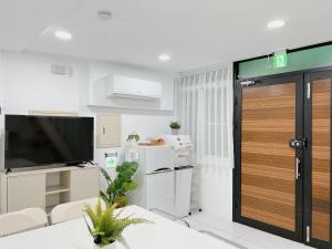 Soda White Tainan Homestay في تاى نان: غرفة معيشة فيها تلفزيون وباب جرار