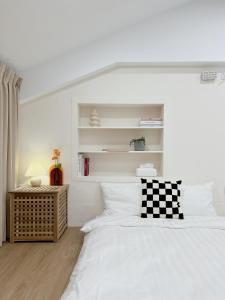 a white bedroom with a bed with a checkered pillow at Soda White Tainan Homestay in Tainan