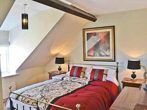 a bedroom with a large bed with a red blanket at Clipper Cottage in Wells next the Sea