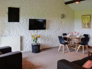 a living room with a table and a tv on a wall at Grooms Cottage in Gilcrux