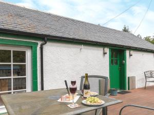 a table with a glass of wine and a plate of food at Bonnies Bothy in Port of Menteith