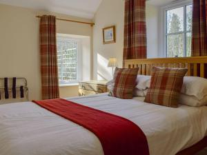 a bedroom with a large bed with a red blanket at Bonnies Bothy in Port of Menteith