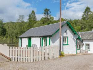 a white house with a fence in front of it at Bonnies Bothy in Port of Menteith