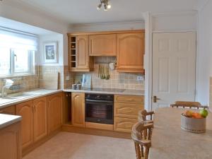 a kitchen with wooden cabinets and a table with a bowl of fruit at Otters in Wroxham