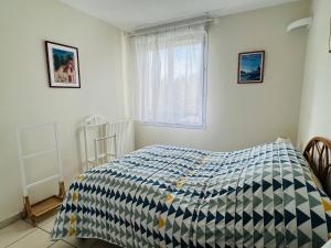 a bedroom with a bed with a blue and white comforter at Appartement Cambo-les-Bains, 2 pièces, 3 personnes - FR-1-495-9 in Cambo-les-Bains