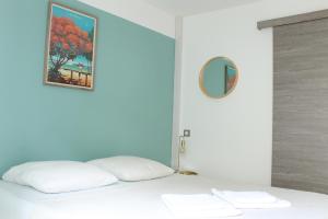 - un lit avec des oreillers blancs et un tableau mural dans l'établissement Fleur de Prunier, à Saint-Pierre