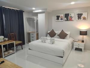 a bedroom with a large white bed and a table at Regent Lodge Lampang in Lampang