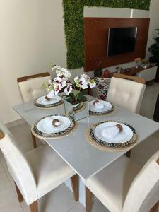 a dining room table with plates and flowers on it at Casa em Brotas Turismo de aventura in Brotas